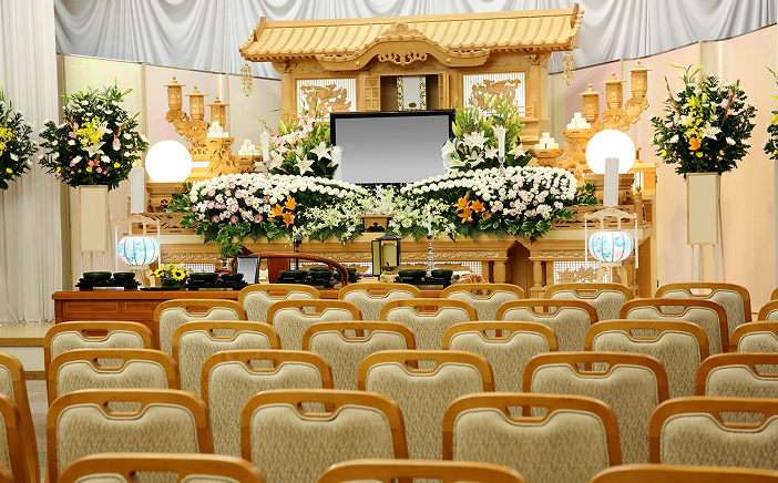 金色の祭壇と生花で飾られた葬儀式場の内観