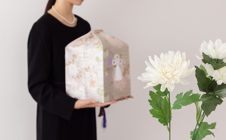 骨壺を持つ喪服姿の女性