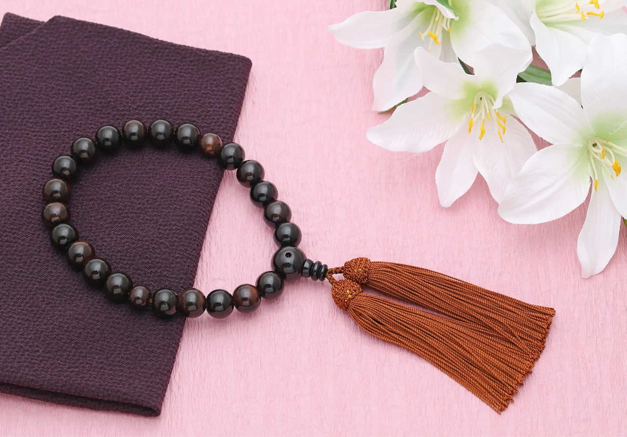 数珠と白いユリの花が添えられた紫色のふくさ